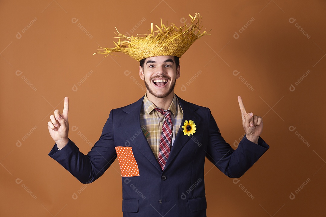 Jovem rapaz vestido a caráter para festa junina com mãos apontando para cima