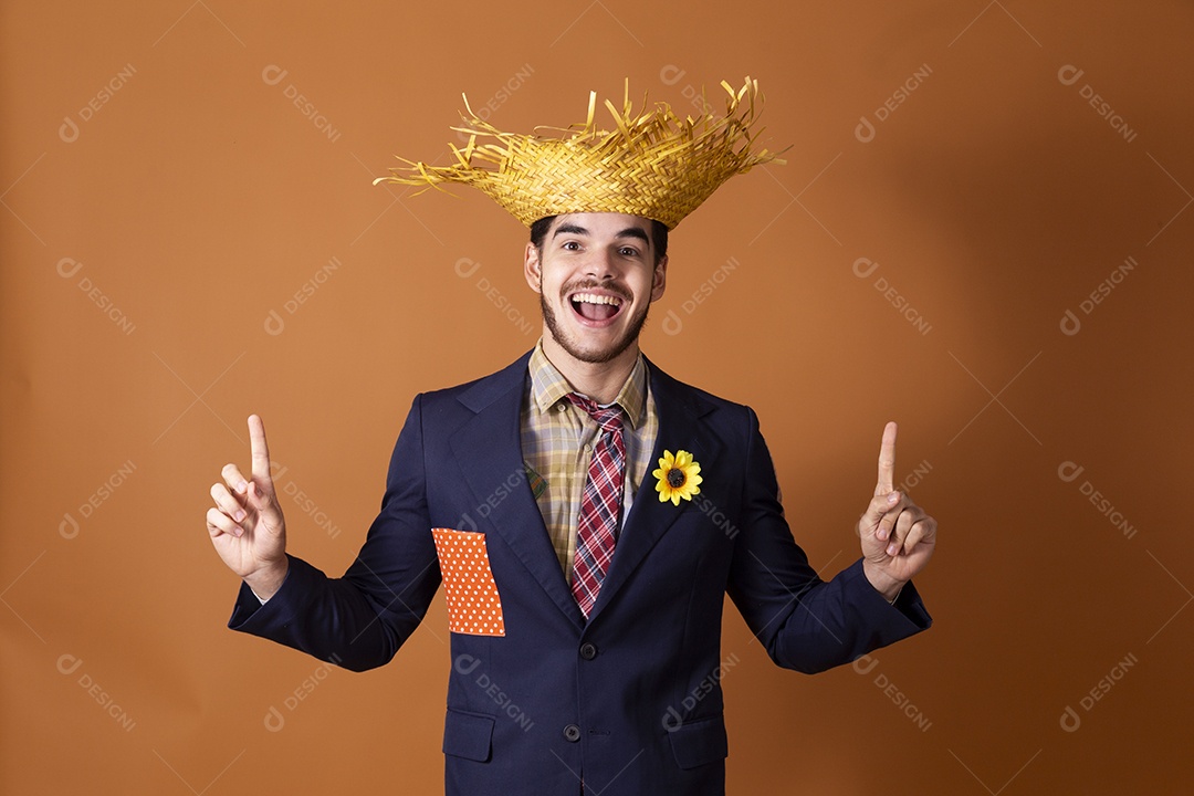 Jovem rapaz sorridente vestido a caráter para festa junina com chapéu nas mãos