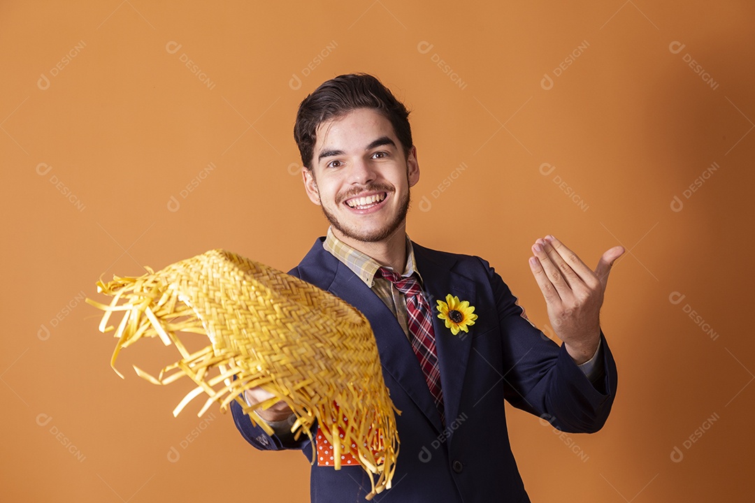 Jovem rapaz vestido a caráter para festa junina com chapéu nas mãos
