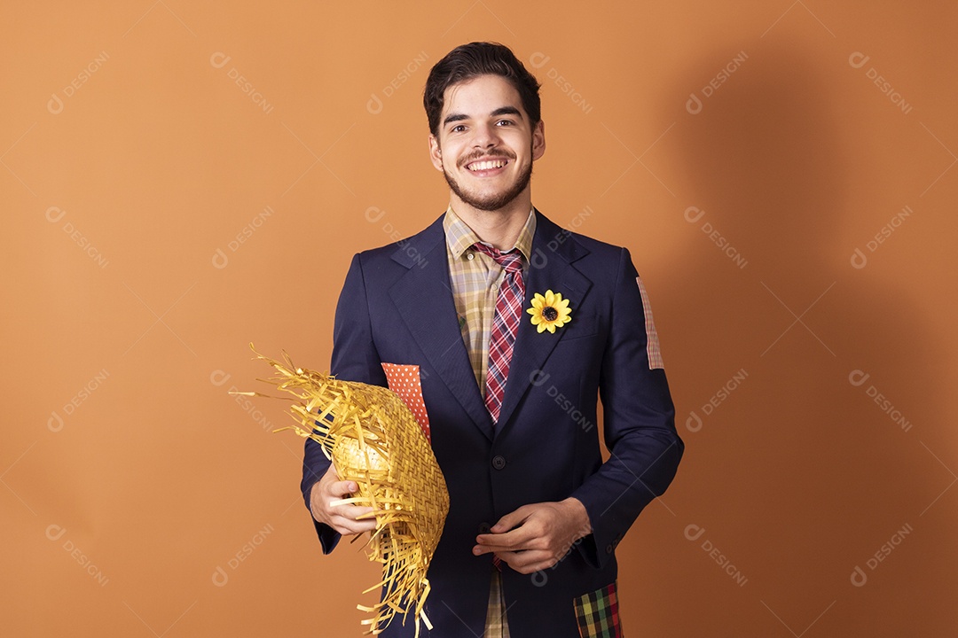 Jovem rapaz vestido a caráter para festa junina com chapéu nas mãos