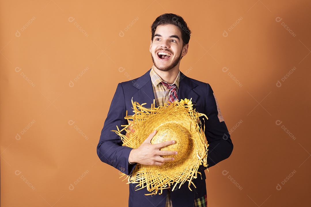 Jovem rapaz vestido a caráter para festa junina com chapéu nas mãos