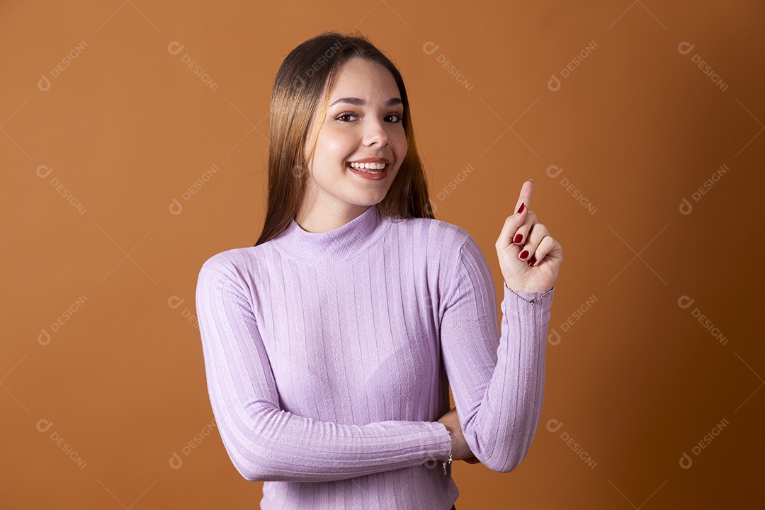 Uma linda jovem de cabelos claros com blusa lilás apontando pra cima