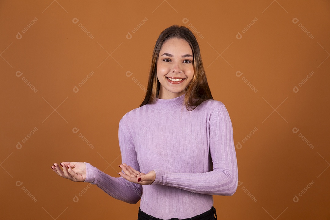 Linda jovem sorridente com blusa lilás e mão para o lado