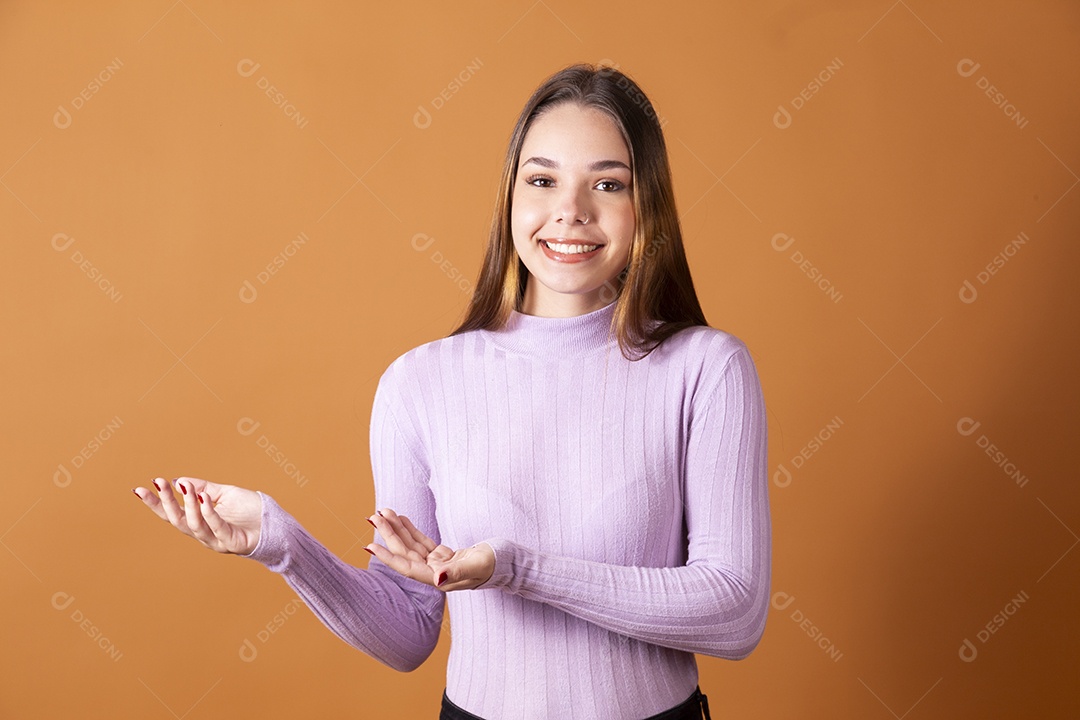 Linda jovem sorridente com blusa lilás e mão para o lado