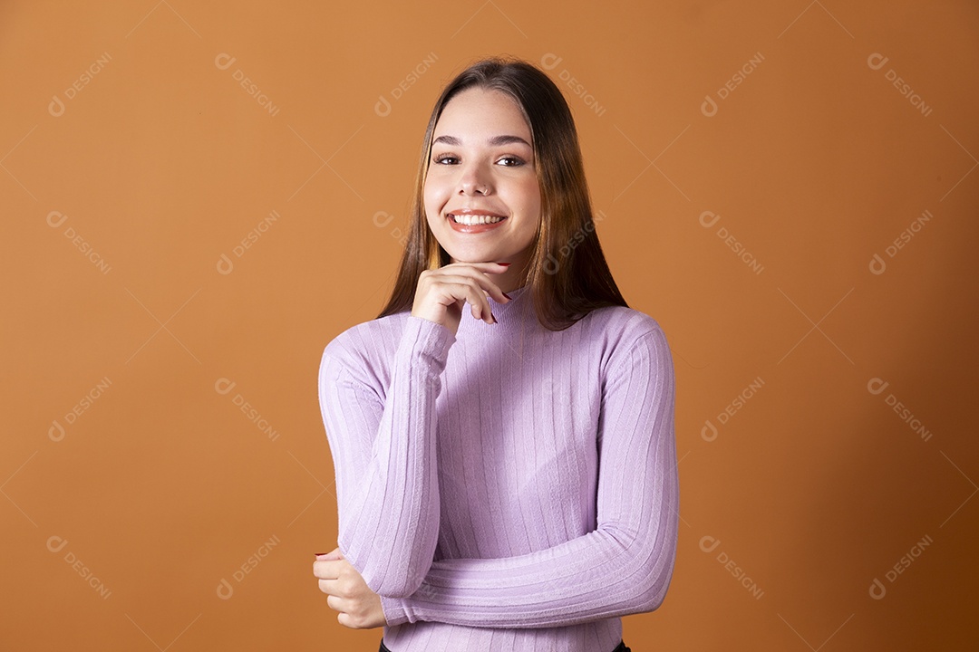 Linda jovem sorridente com blusa lilás e mão no queixo