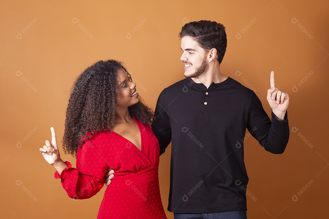 Casal de jovens se olhando abraçados e apontando para algo