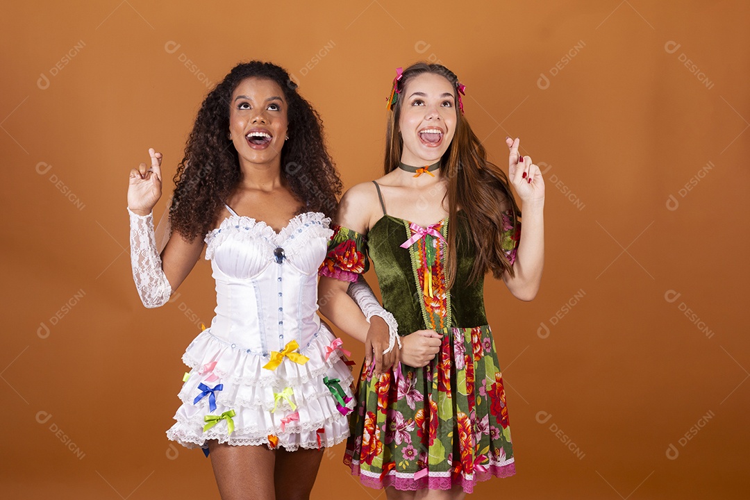 Duas jovem bonitas trajadas para festa junina com dedos cruzados