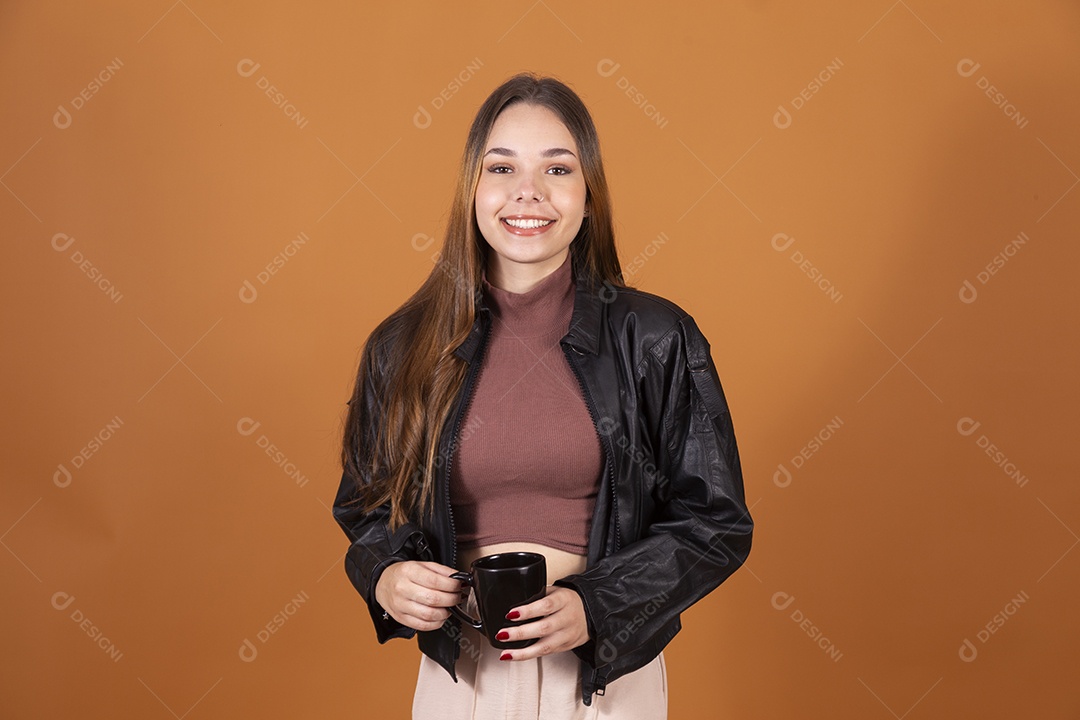 Jovem linda de cabelos claros com jaqueta preta tomando algo em xícara