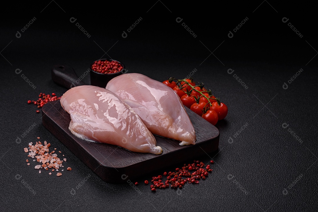 Filé de frango fresco sobre uma mesa de concreto escuro com especiarias e ervas. Preparação para cozinhar pratos de carne