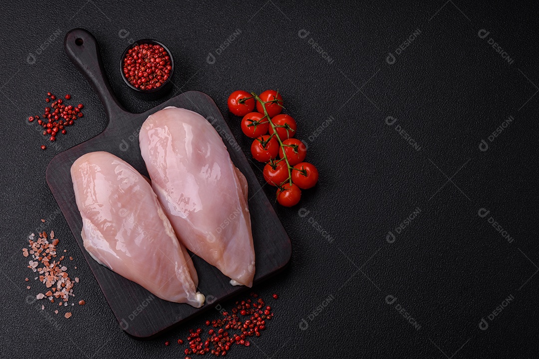 Filé de frango fresco sobre uma mesa de concreto escuro com especiarias e ervas. Preparação para cozinhar pratos de carne