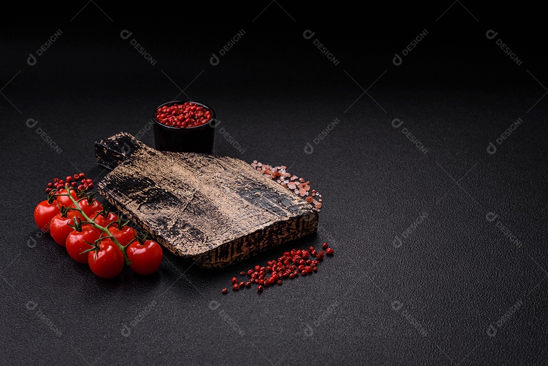 Fundo preto com tomate cereja, sal, especiarias e ervas. Ingredientes culinários