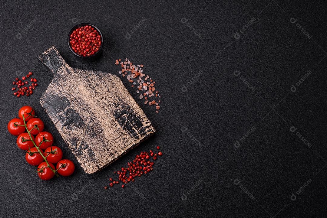 Fundo preto com tomate cereja, sal, especiarias e ervas. Ingredientes culinários