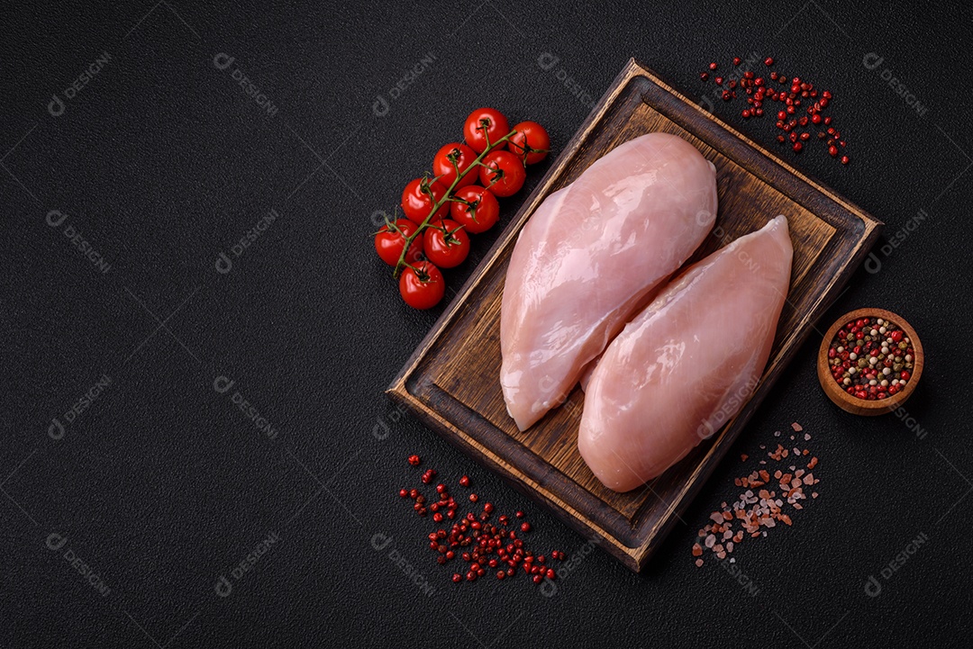 Filé de frango fresco sobre uma mesa de concreto escuro com especiarias e ervas. Preparação para cozinhar pratos de carne