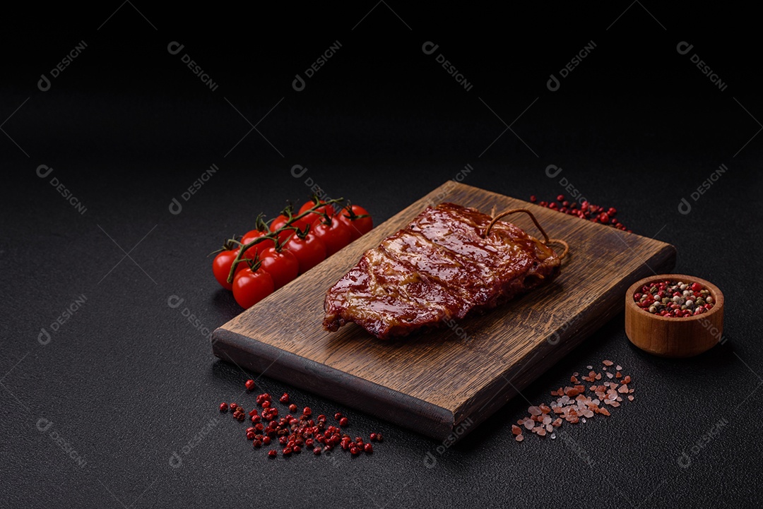 Deliciosas costelas grelhadas assadas na grelha com sal, especiarias e ervas sobre um fundo escuro de concreto