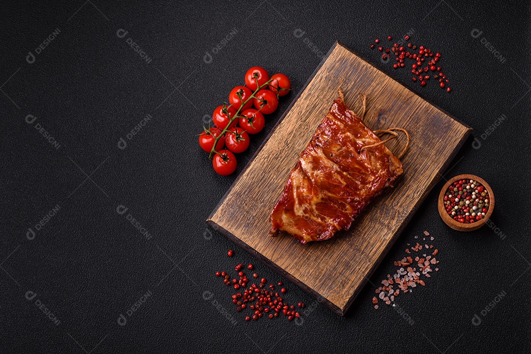 Deliciosas costelas grelhadas assadas na grelha com sal, especiarias e ervas sobre um fundo escuro de concreto