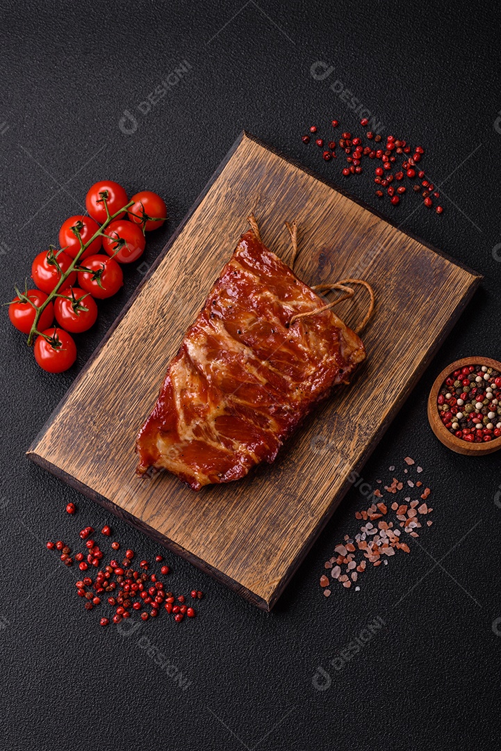 Deliciosas costelas grelhadas assadas na grelha com sal, especiarias e ervas sobre um fundo escuro de concreto