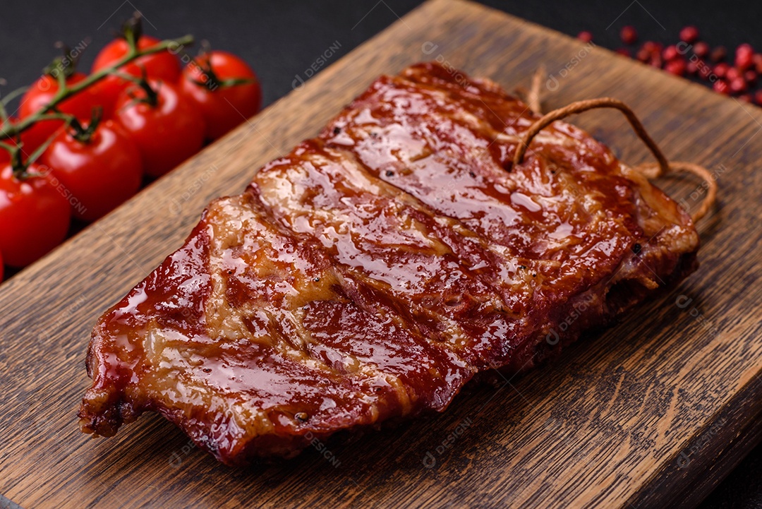 Deliciosas costelas grelhadas assadas na grelha com sal, especiarias e ervas sobre um fundo escuro de concreto