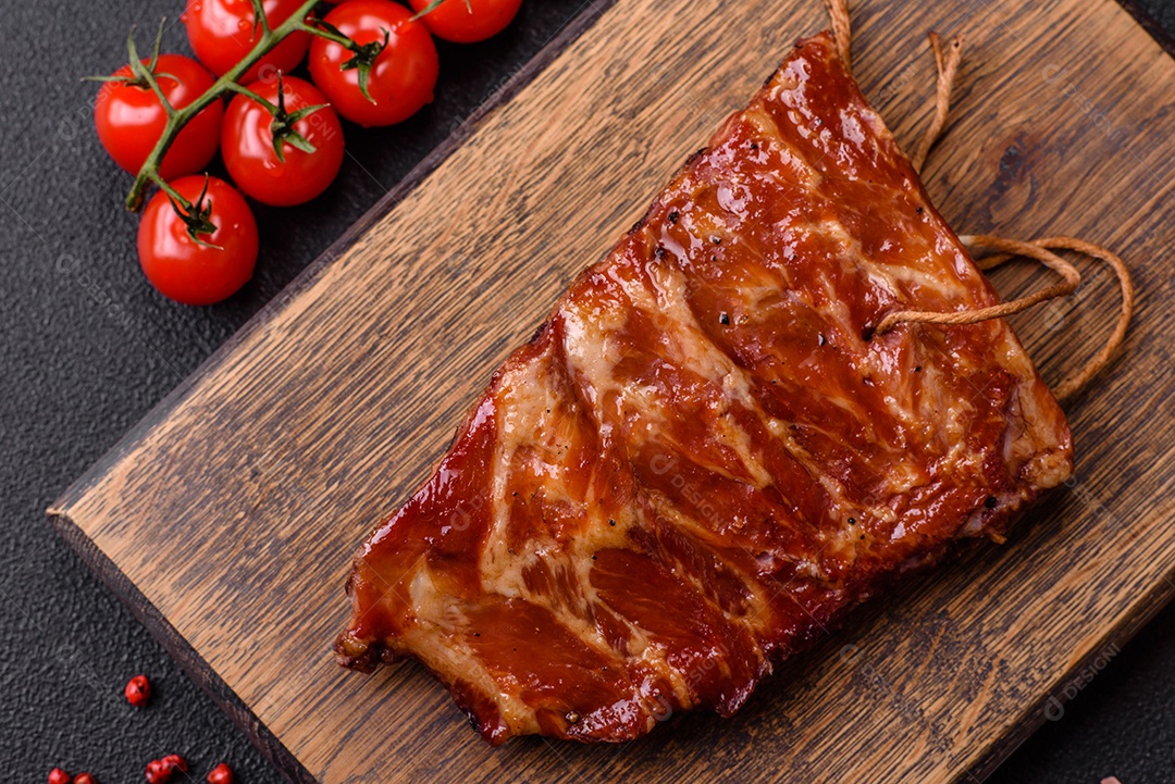 Deliciosas costelas grelhadas assadas na grelha com sal, especiarias e ervas sobre um fundo escuro de concreto