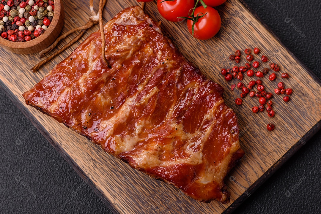 Deliciosas costelas grelhadas assadas na grelha com sal, especiarias e ervas sobre um fundo escuro de concreto