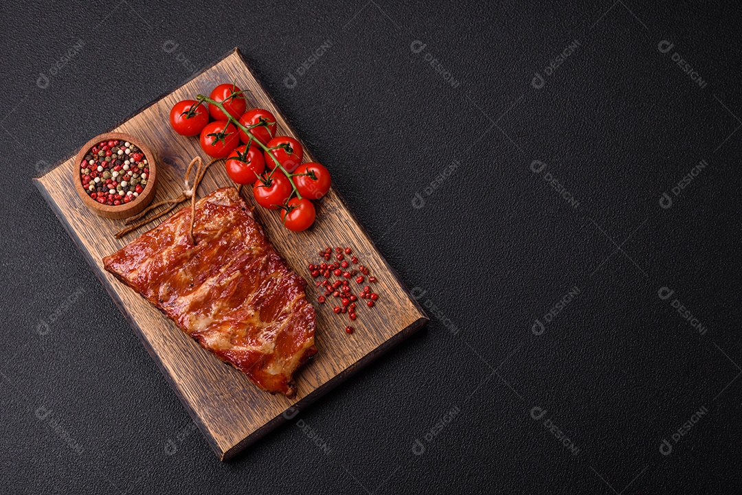 Deliciosas costelas grelhadas assadas na grelha com sal, especiarias e ervas sobre um fundo escuro de concreto