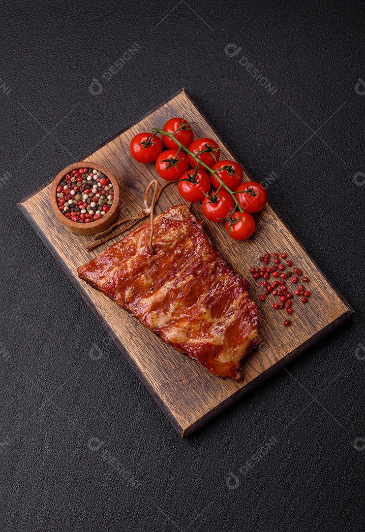 Deliciosas costelas grelhadas assadas na grelha com sal, especiarias e ervas sobre um fundo escuro de concreto