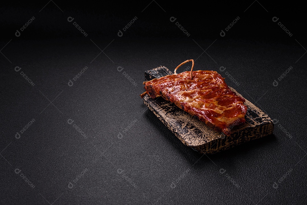 Deliciosas costelas grelhadas assadas na grelha com sal, especiarias e ervas sobre um fundo escuro de concreto