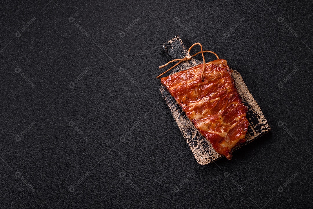 Deliciosas costelas grelhadas assadas na grelha com sal, especiarias e ervas sobre um fundo escuro de concreto