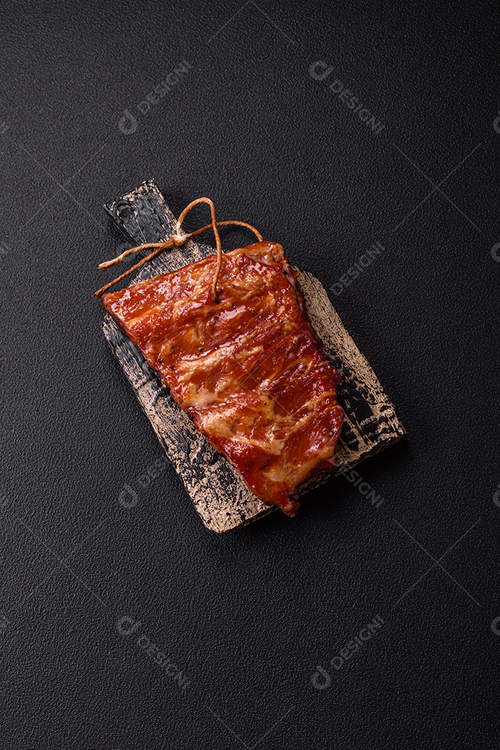 Deliciosas costelas grelhadas assadas na grelha com sal, especiarias e ervas sobre um fundo escuro de concreto