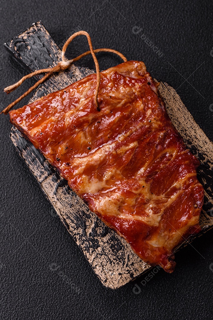 Deliciosas costelas grelhadas assadas na grelha com sal, especiarias e ervas sobre um fundo escuro de concreto