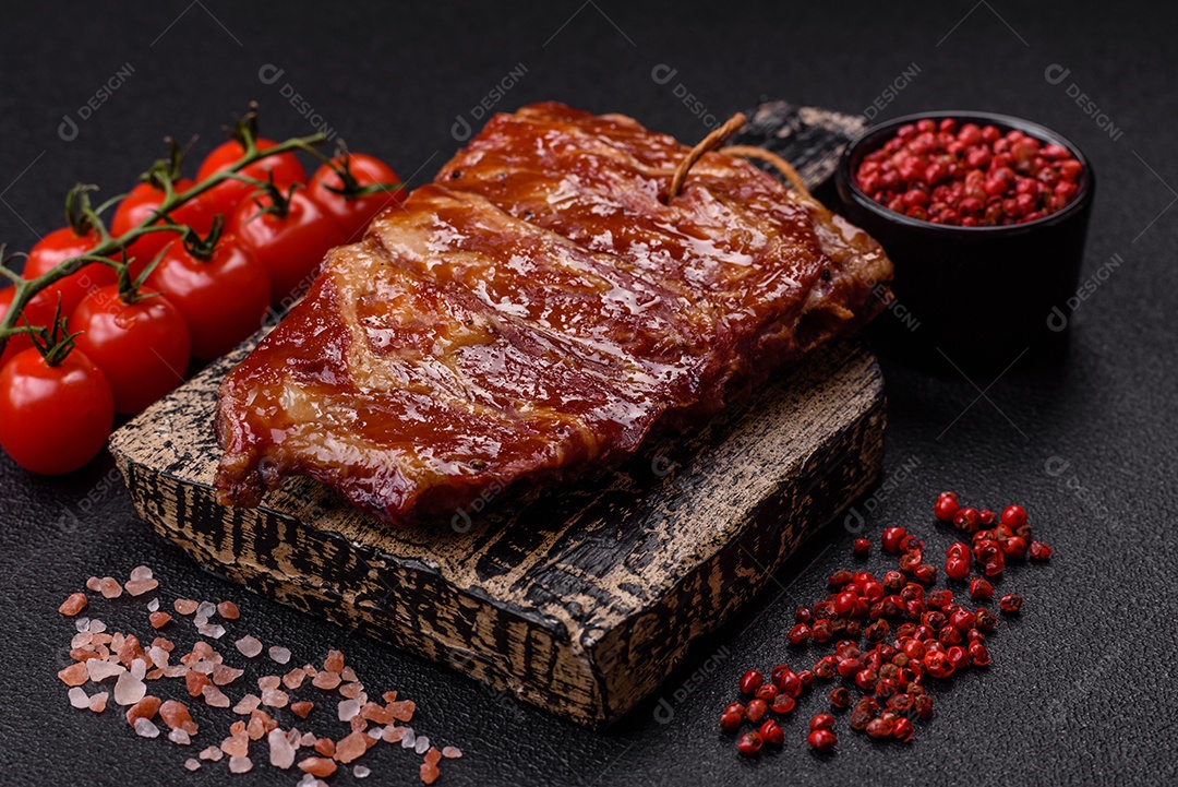 Deliciosas costelas grelhadas assadas na grelha com sal, especiarias e ervas sobre um fundo escuro de concreto