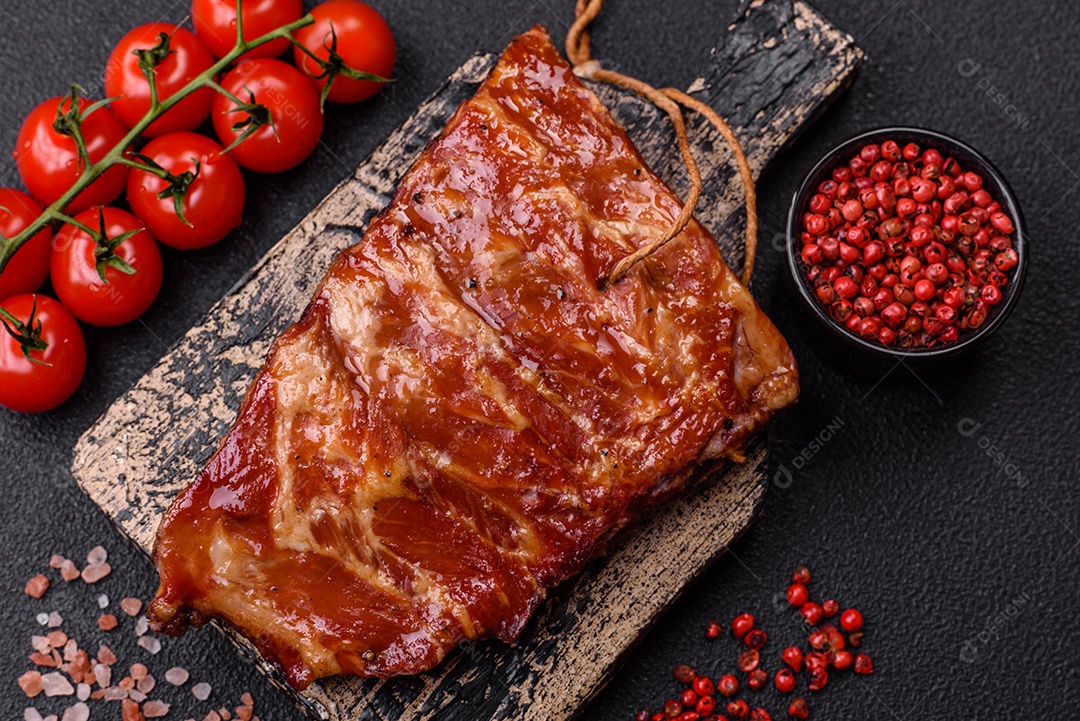 Deliciosas costelas grelhadas assadas na grelha com sal, especiarias e ervas sobre um fundo escuro de concreto