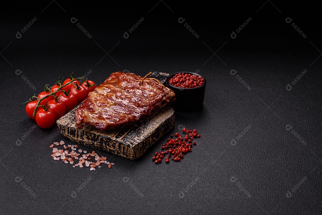 Deliciosas costelas grelhadas assadas na grelha com sal, especiarias e ervas sobre um fundo escuro de concreto