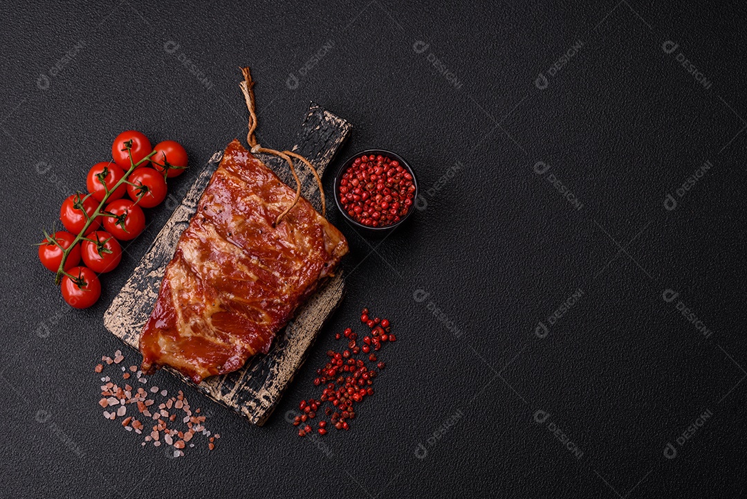 Deliciosas costelas grelhadas assadas na grelha com sal, especiarias e ervas sobre um fundo escuro de concreto