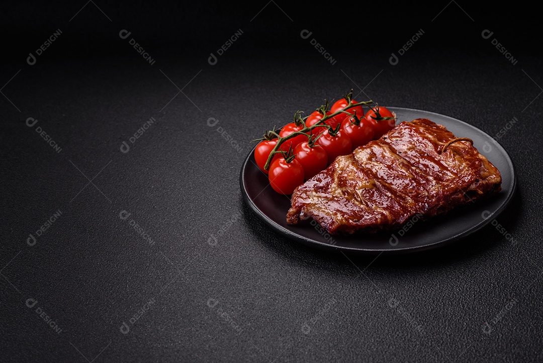 Deliciosas costelas grelhadas assadas na grelha com sal, especiarias e ervas sobre um fundo escuro de concreto