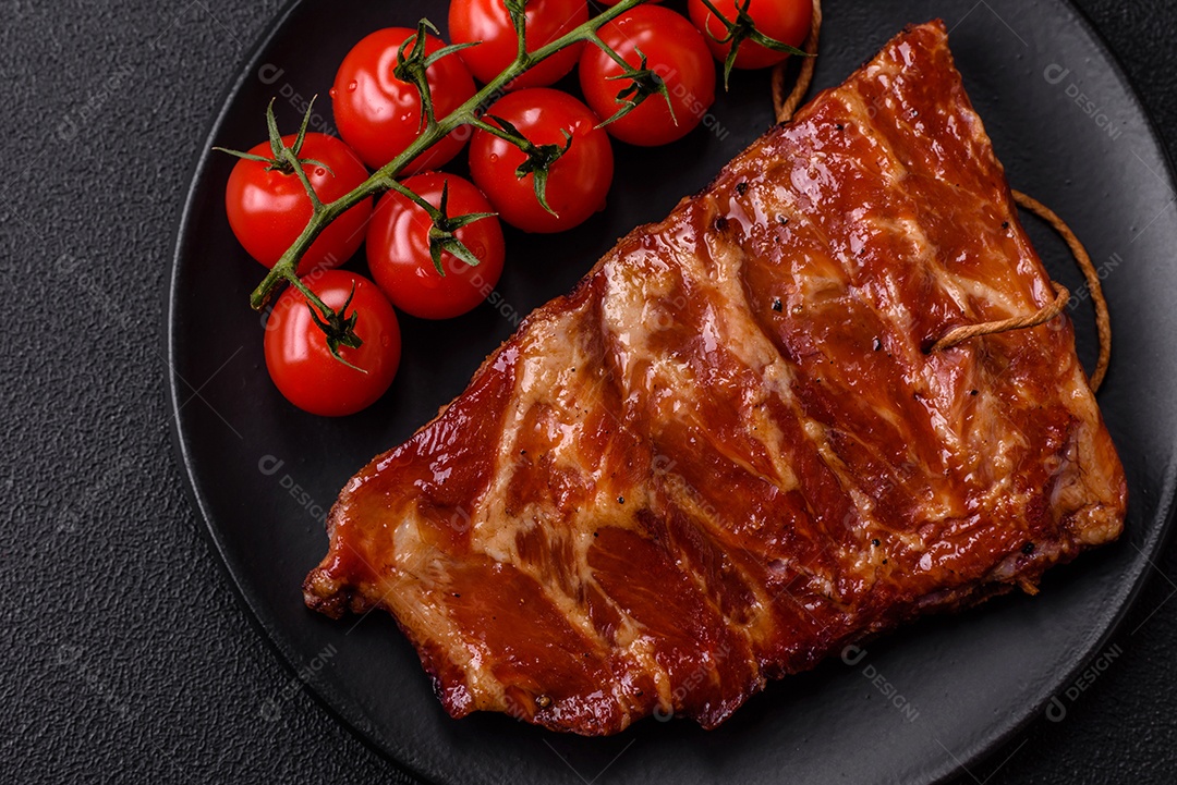 Deliciosas costelas grelhadas assadas na grelha com sal, especiarias e ervas sobre um fundo escuro de concreto