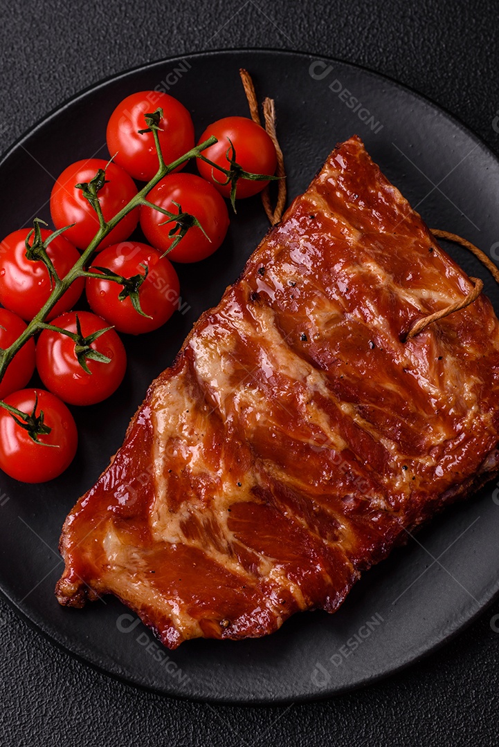 Deliciosas costelas grelhadas assadas na grelha com sal, especiarias e ervas sobre um fundo escuro de concreto