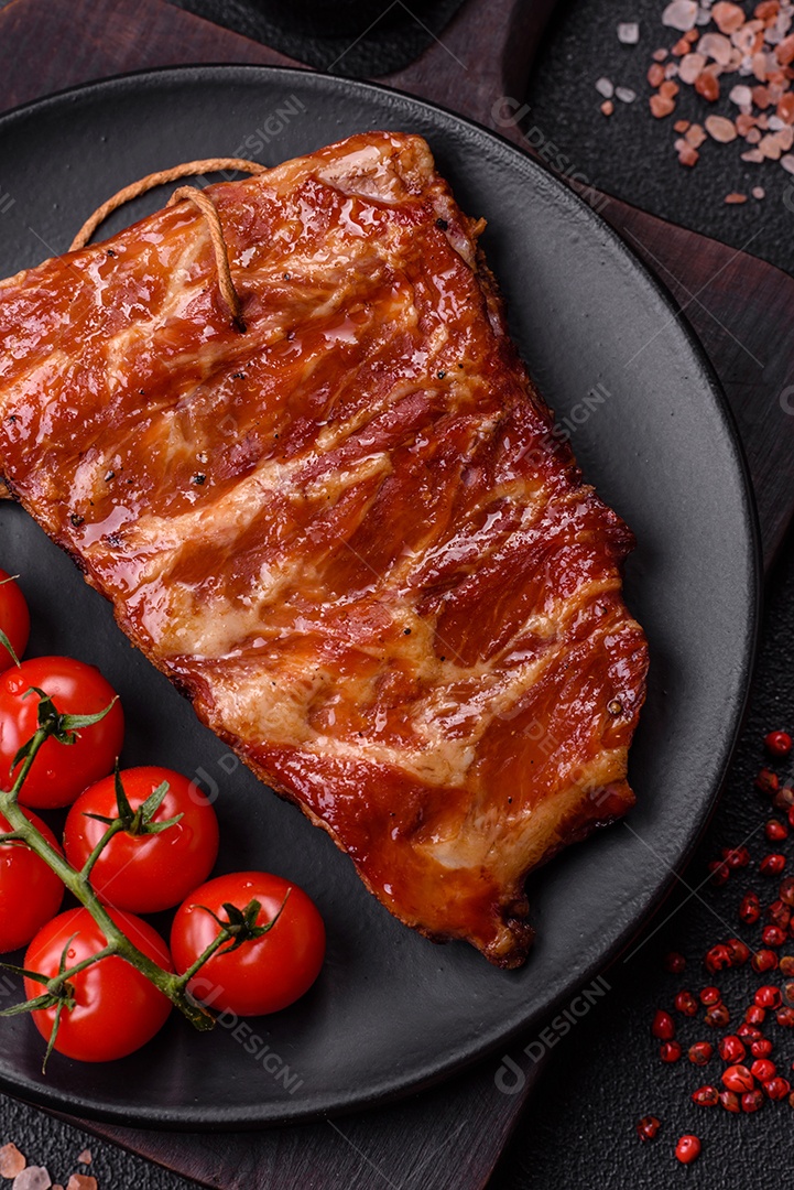 Deliciosas costelas grelhadas assadas na grelha com sal, especiarias e ervas sobre um fundo escuro de concreto