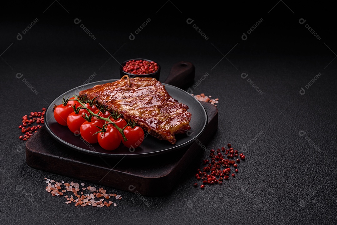 Deliciosas costelas grelhadas assadas na grelha com sal, especiarias e ervas sobre um fundo escuro de concreto