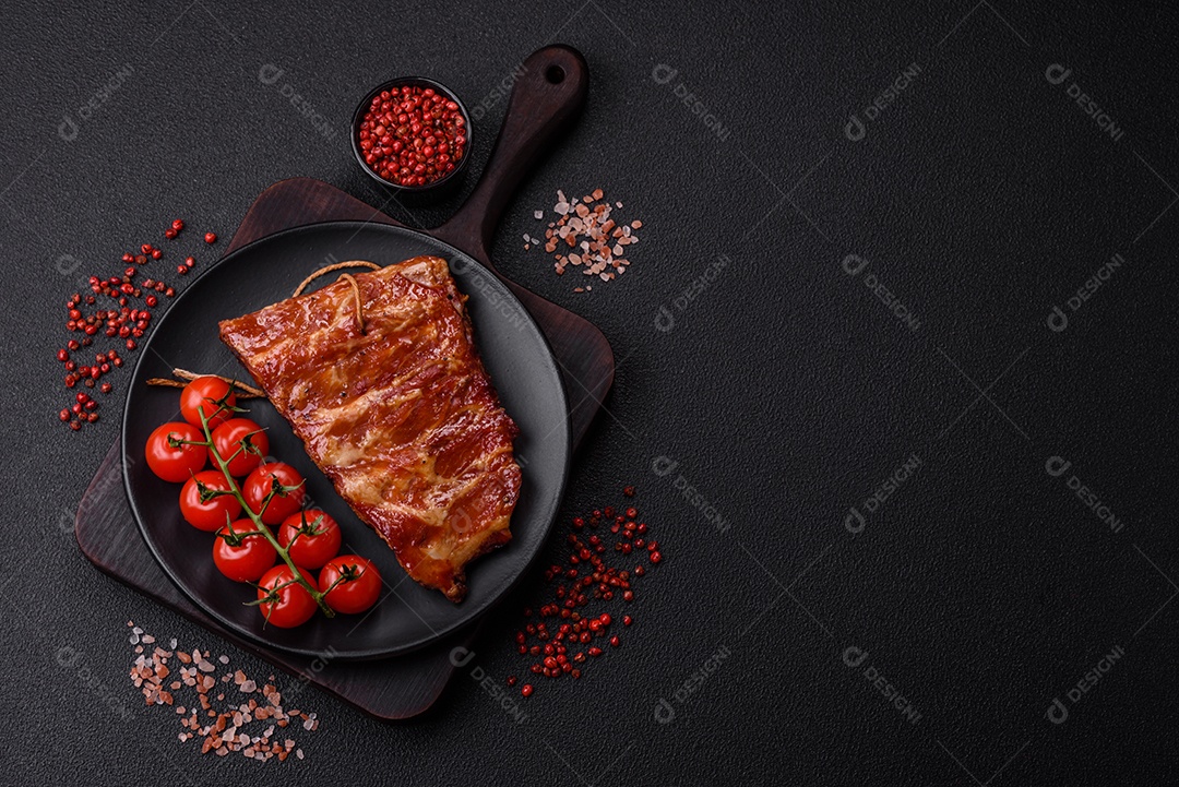 Deliciosas costelas grelhadas assadas na grelha com sal, especiarias e ervas sobre um fundo escuro de concreto