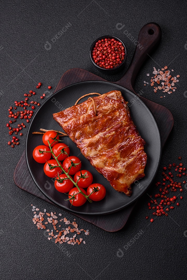 Deliciosas costelas grelhadas assadas na grelha com sal, especiarias e ervas sobre um fundo escuro de concreto
