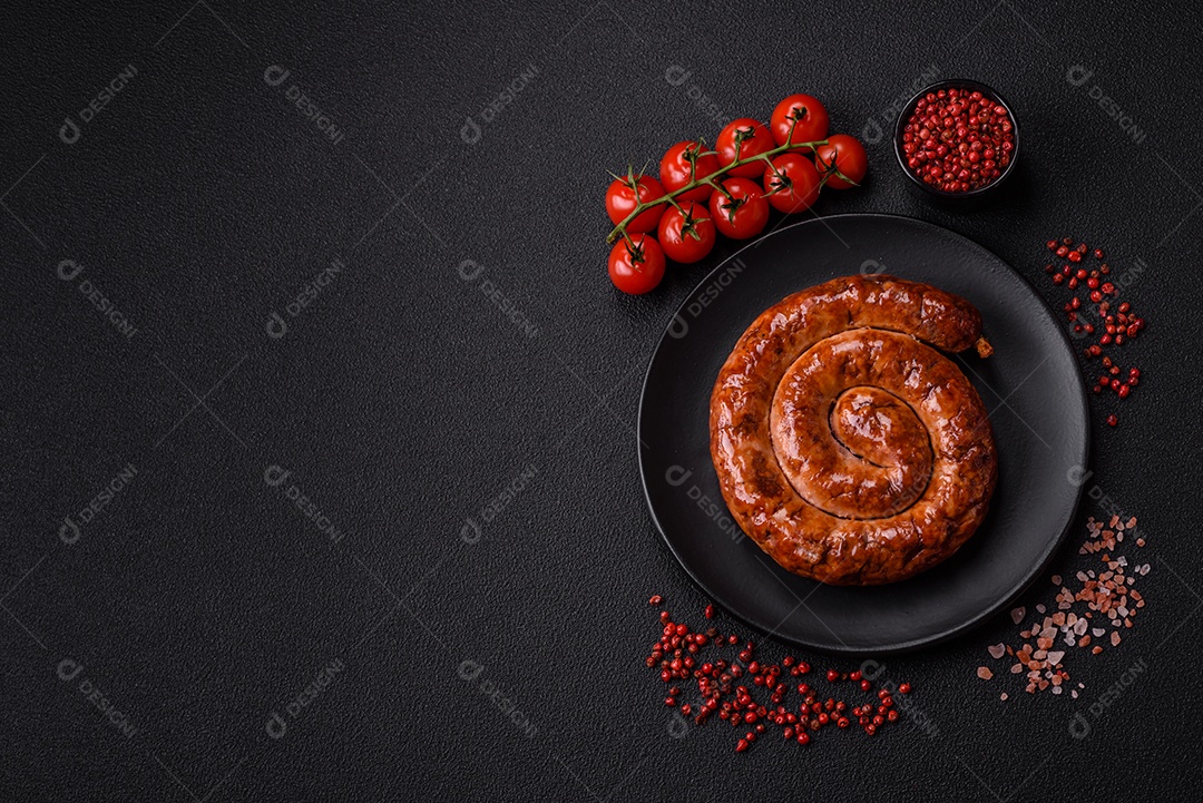Deliciosa salsicha caseira em forma de espiral assada na grelha com sal, especiarias e ervas sobre um fundo escuro de concreto