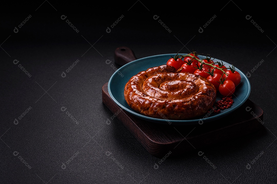 Deliciosa salsicha caseira em forma de espiral assada na grelha com sal, especiarias e ervas sobre um fundo escuro de concreto