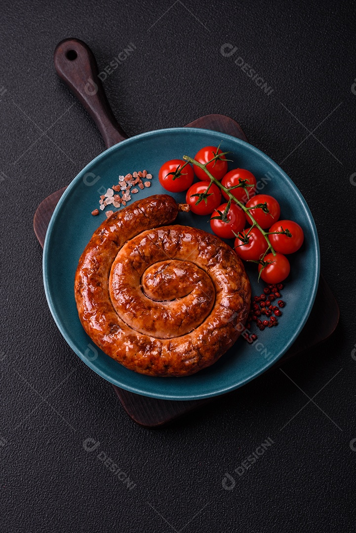 Deliciosa salsicha caseira em forma de espiral assada na grelha com sal, especiarias e ervas sobre um fundo escuro de concreto