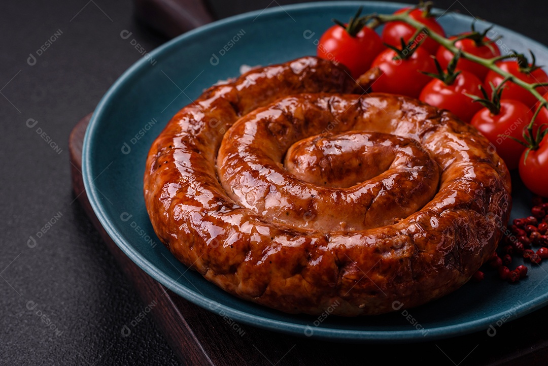 Deliciosa salsicha caseira em forma de espiral assada na grelha com sal, especiarias e ervas sobre um fundo escuro de concreto