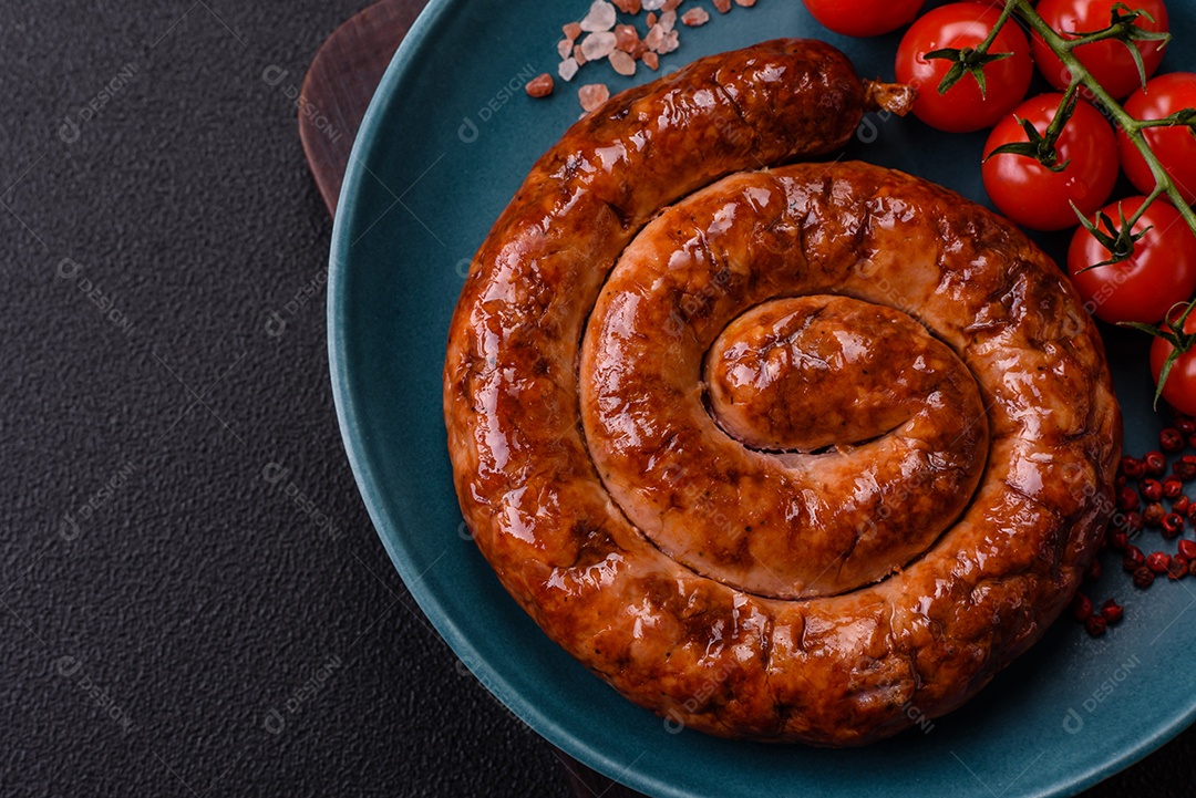 Deliciosa salsicha caseira em forma de espiral assada na grelha com sal, especiarias e ervas sobre um fundo escuro de concreto