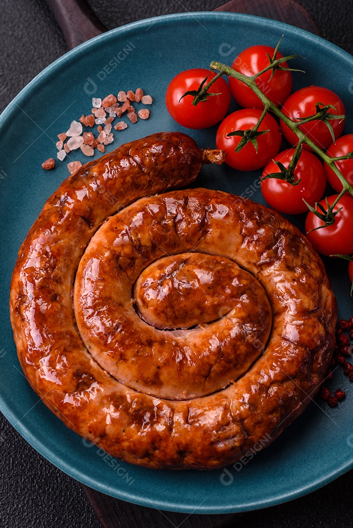 Deliciosa salsicha caseira em forma de espiral assada na grelha com sal, especiarias e ervas sobre um fundo escuro de concreto