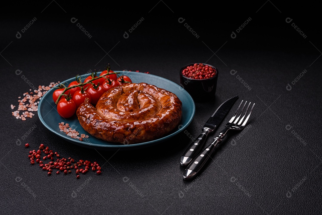 Deliciosa salsicha caseira em forma de espiral assada na grelha com sal, especiarias e ervas sobre um fundo escuro de concreto
