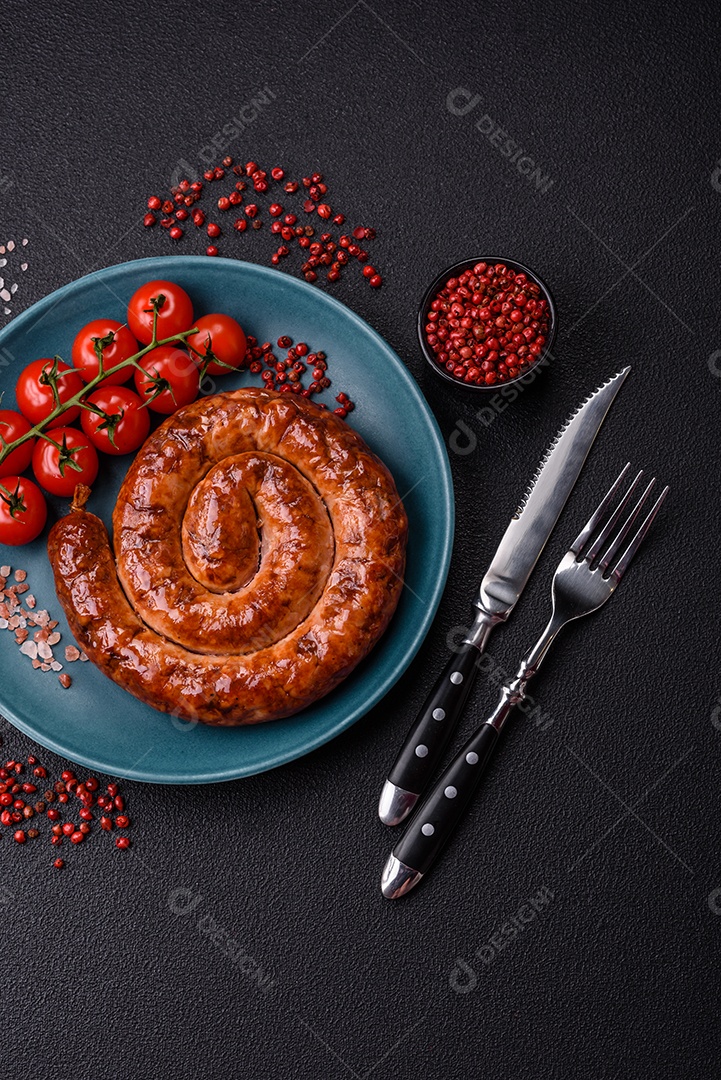 Deliciosa salsicha caseira em forma de espiral assada na grelha com sal, especiarias e ervas sobre um fundo escuro de concreto