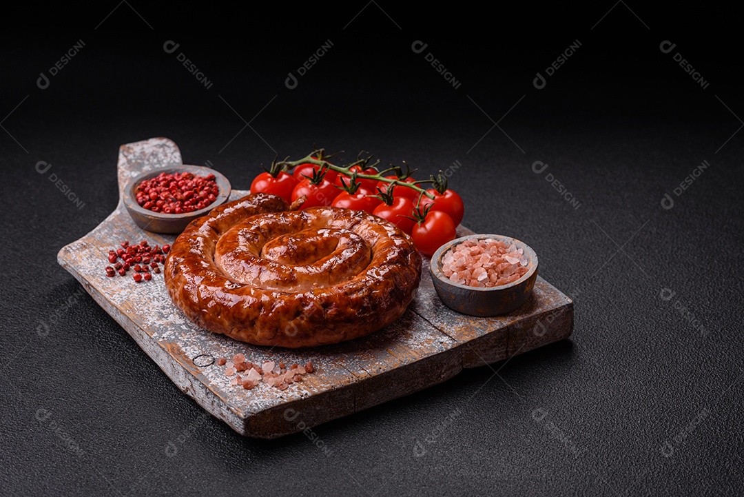 Deliciosa salsicha caseira em forma de espiral assada na grelha com sal, especiarias e ervas sobre um fundo escuro de concreto