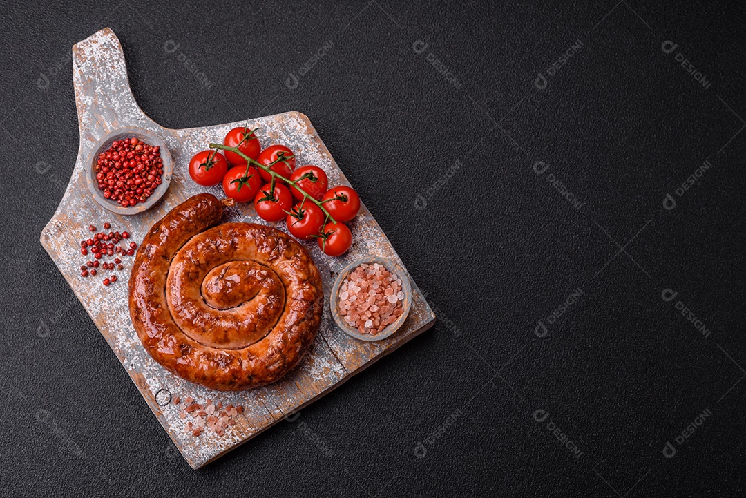 Deliciosa salsicha caseira em forma de espiral assada na grelha com sal, especiarias e ervas sobre um fundo escuro de concreto